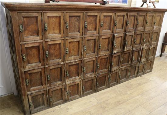 A large 19th century Continental pitch pine forty door locker cabinet W.299cm